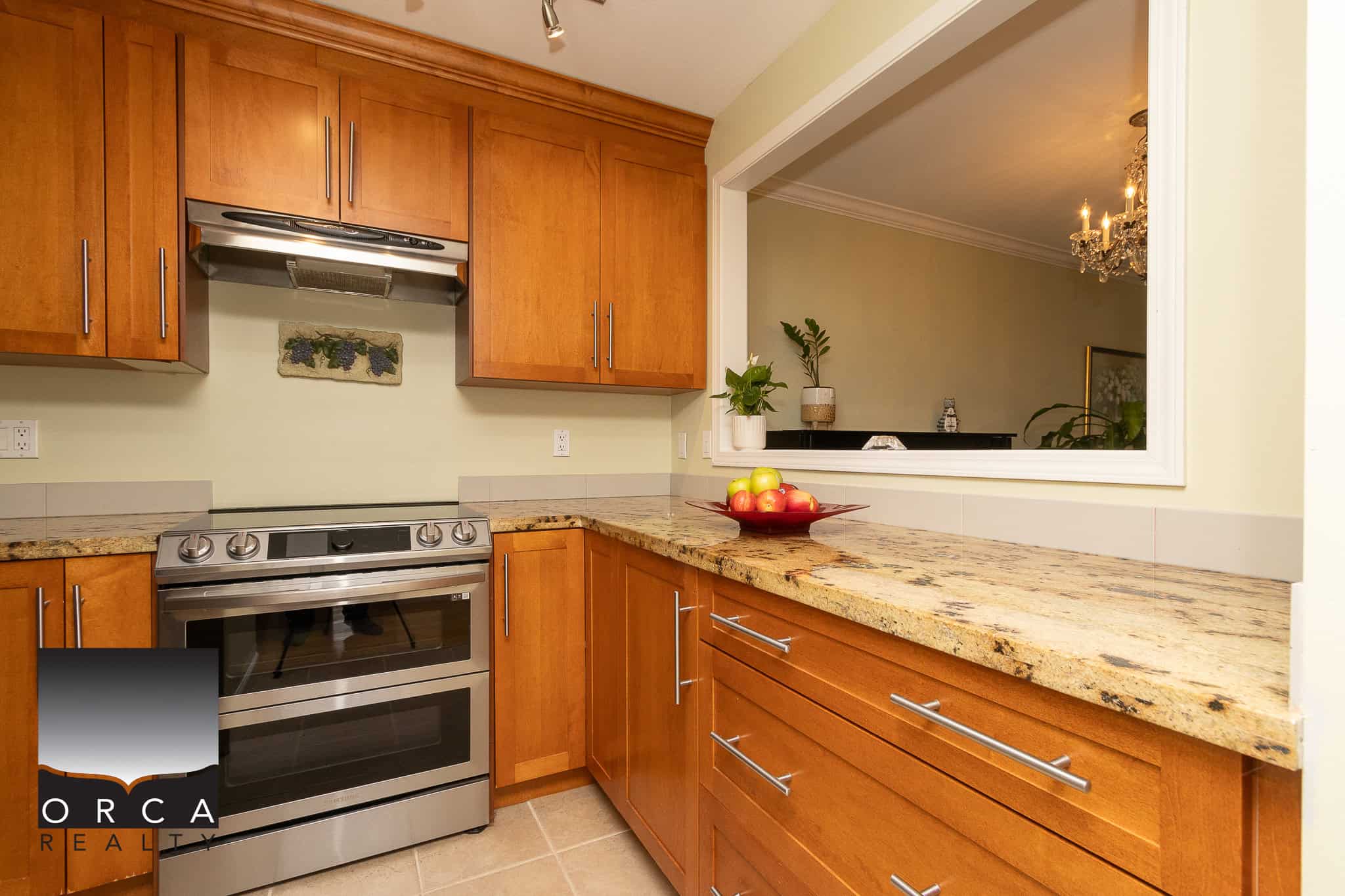 Modern kitchen with warm wood cabinetry, granite countertops, stainless steel appliances, and an open window view, ideal for Vancouver Island real estate and home buyers seeking stylish, functional kitchens.