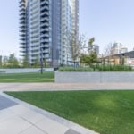 Modern urban outdoor space with landscaped greenery and high-rise residential buildings, ideal for real estate investors and homebuyers in Vancouver.