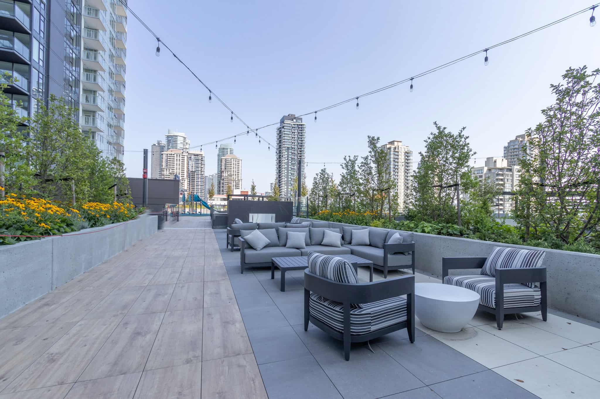 Spacious outdoor rooftop terrace with modern seating and city skyline views, perfect for relaxation and entertaining in Vancouver's residential communities.