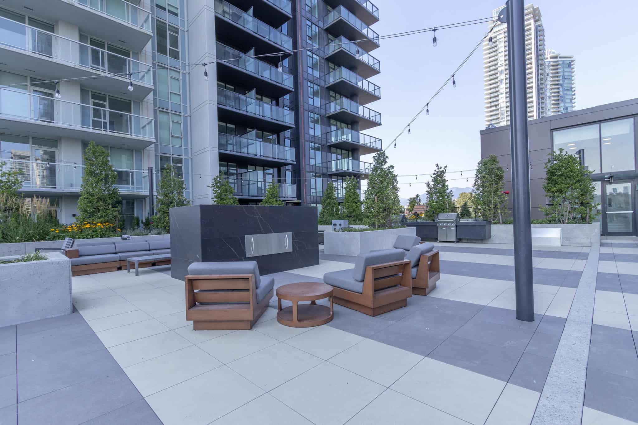 Modern outdoor lounge area at Orca Realty Inc. showcasing contemporary residential complex amenities with landscaped greenery and outdoor seating for residents.