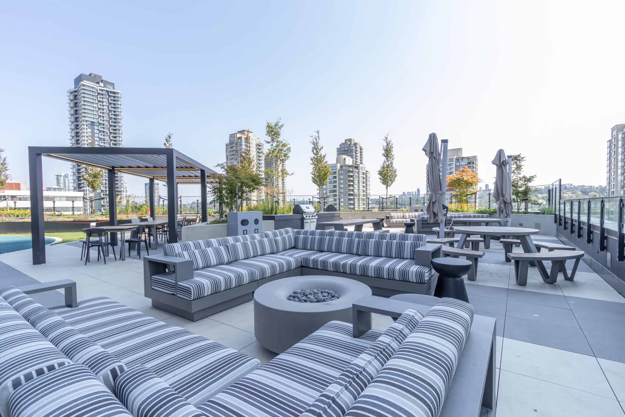 Modern rooftop terrace with outdoor seating, loungers, and city skyline views in Vancouver, BC. Perfect for relaxation and entertaining in luxury condos by Orca Realty Inc.