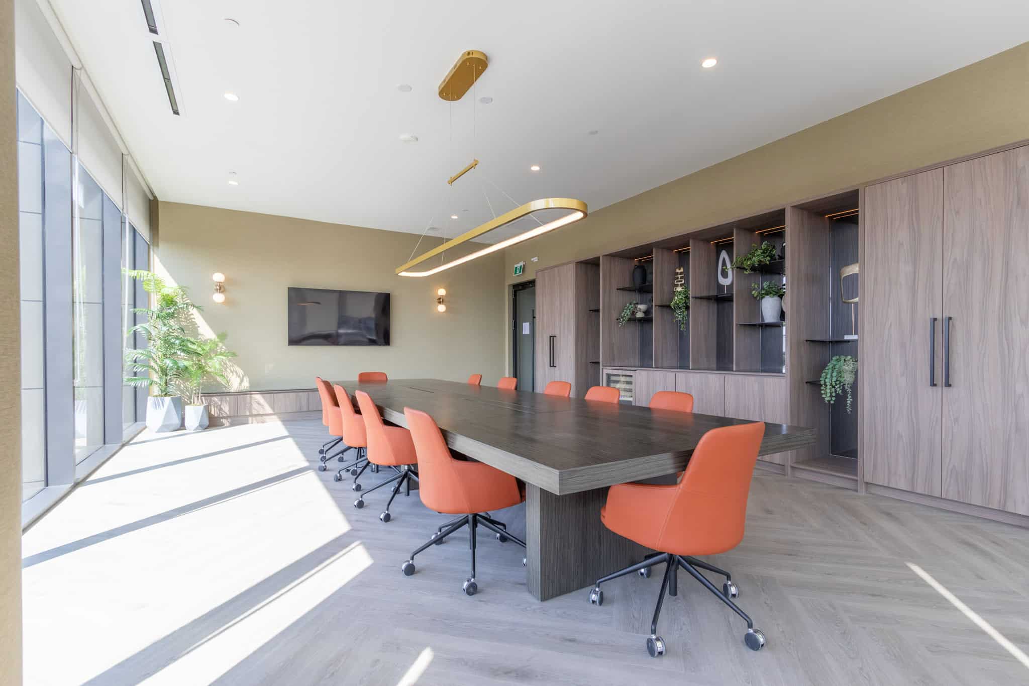 Modern real estate office conference room with natural light, contemporary decor, and vibrant orange chairs, ideal for client meetings and property consultations.