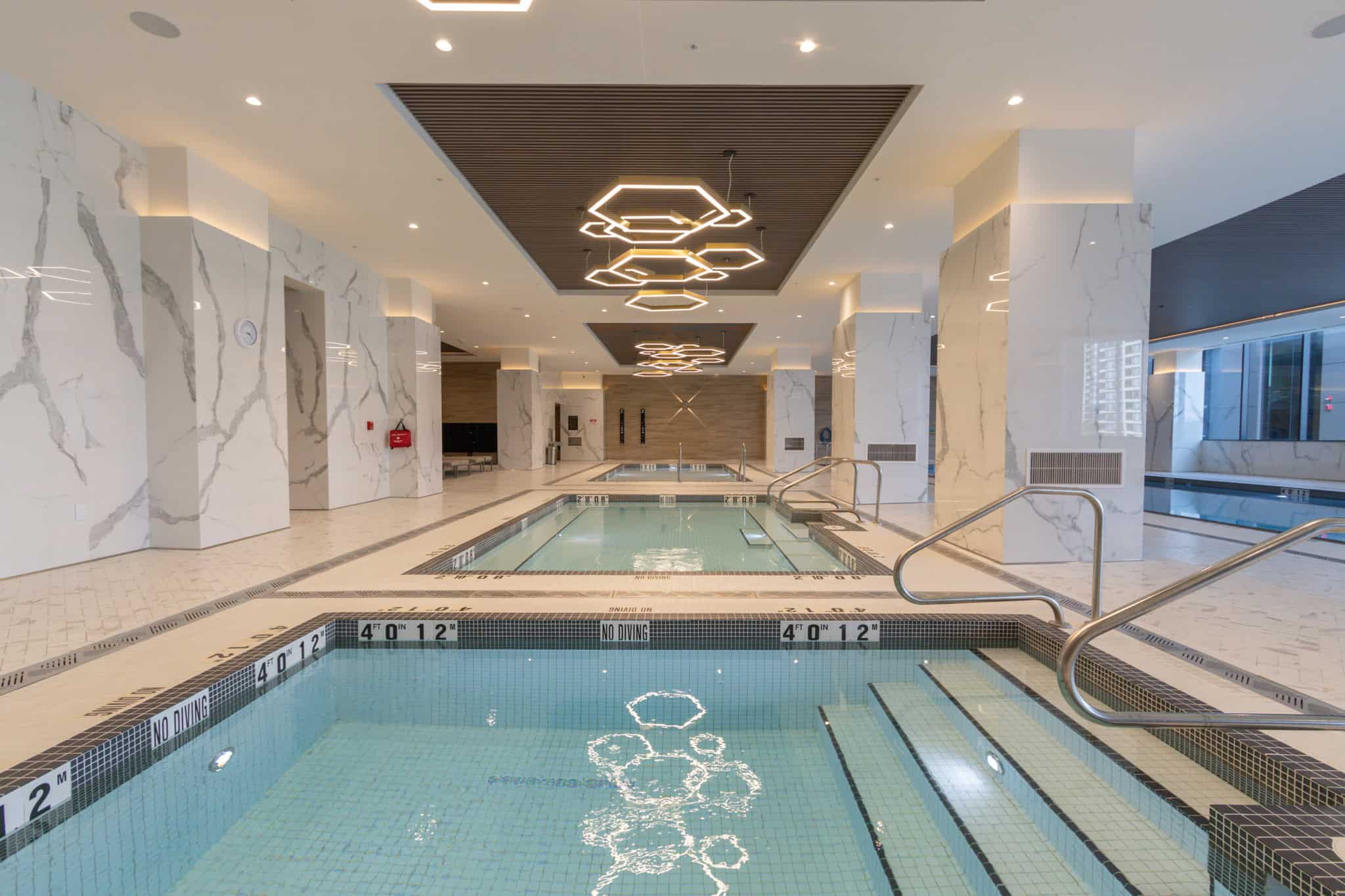 Luxurious indoor swimming pool with modern lighting and elegant marble walls at Orca Realty Inc. office building in Vancouver, BC. Perfect for relaxation and wellness.