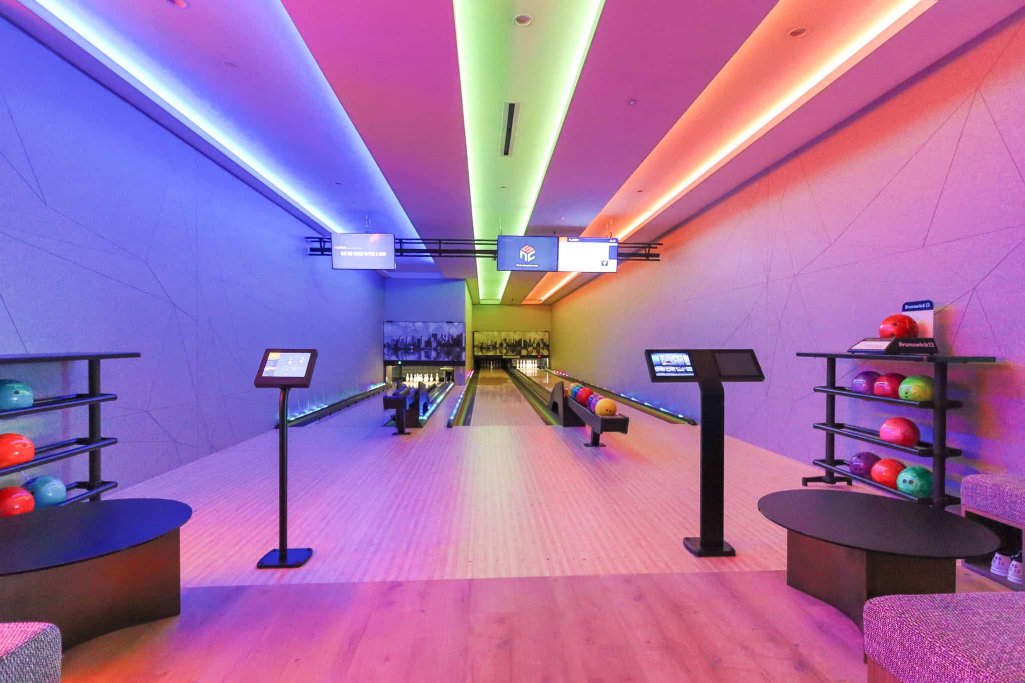 Vibrant upscale indoor bowling alley at Orca Realty Inc. featuring colorful LED lighting, modern lanes, and comfortable seating, perfect for entertaining and real estate showcase events.