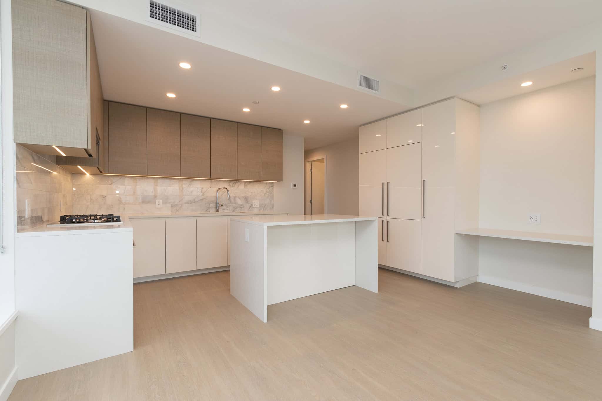 Modern minimalist kitchen with white cabinetry, marble backsplash, and ample storage space, perfect for Vancouver real estate listings.