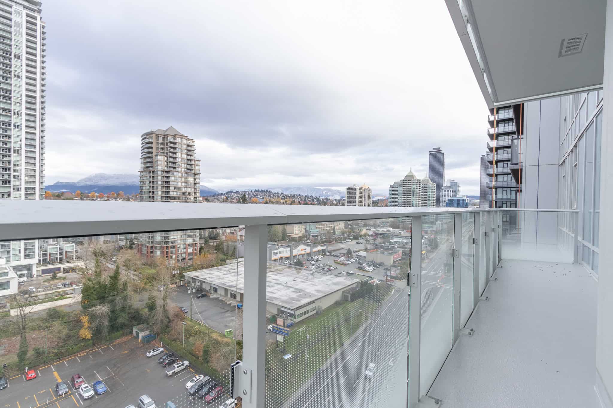 Modern urban balcony with city skyline views in Vancouver, BC, featuring high-rise buildings and mountain backdrop, ideal for condo living and real estate investments.