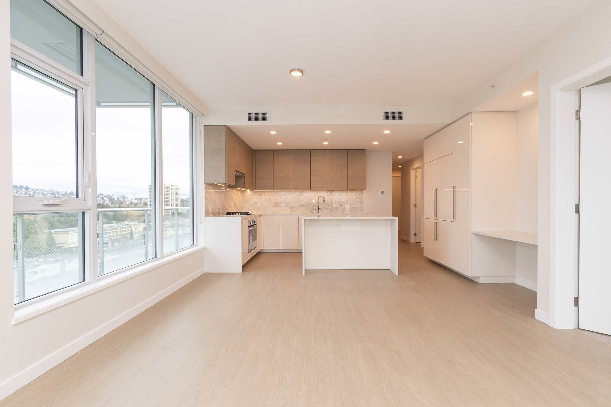 Bright modern open-concept kitchen and living area in a Vancouver apartment, featuring large windows, contemporary cabinetry, and sleek design, perfect for upscale urban living.