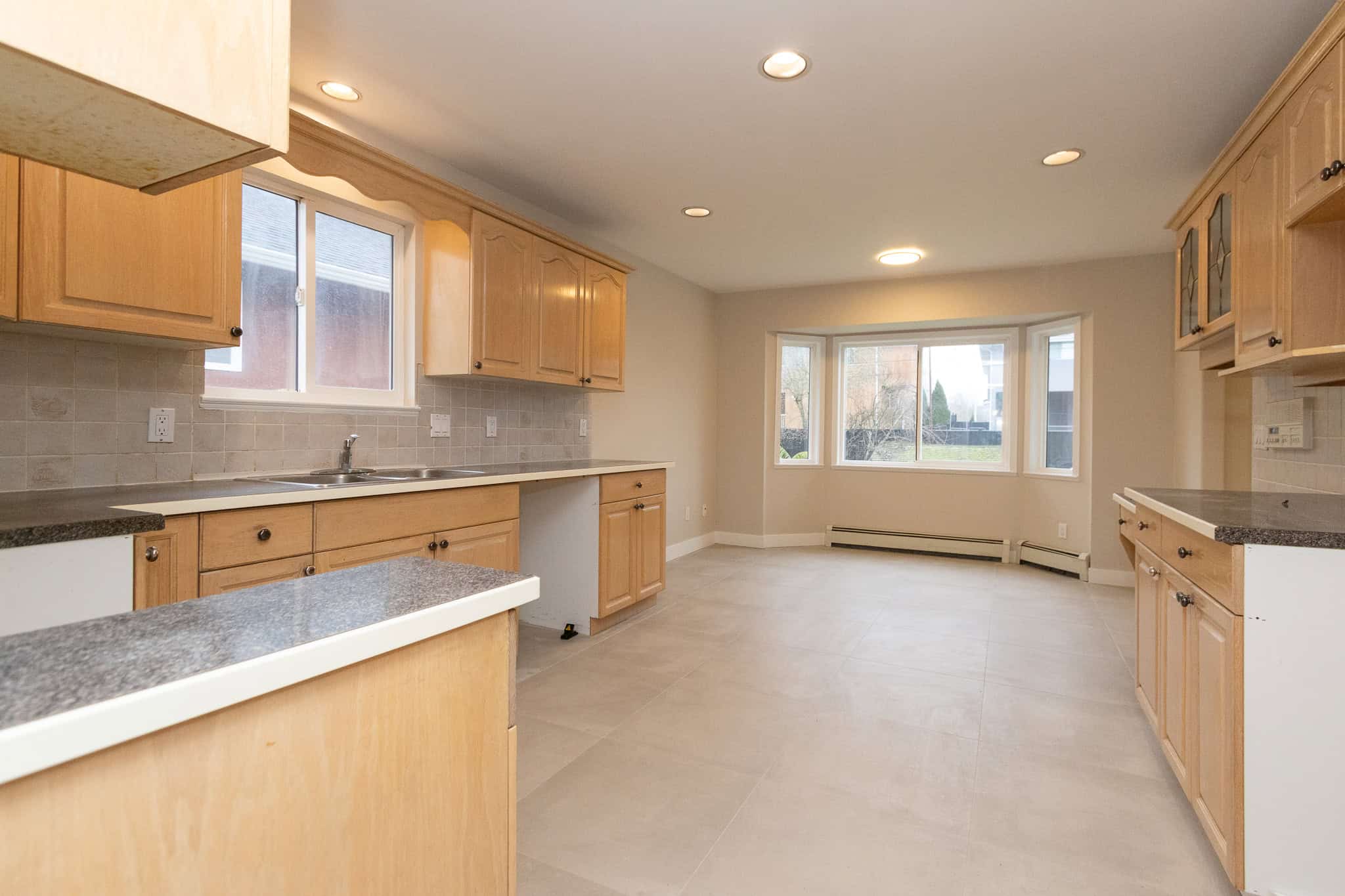 IMG_4329 Bright spacious kitchen with natural light, honey-colored wooden cabinets, granite countertops, and modern appliances, perfect for Vancouver Island homebuyers and real estate investors.