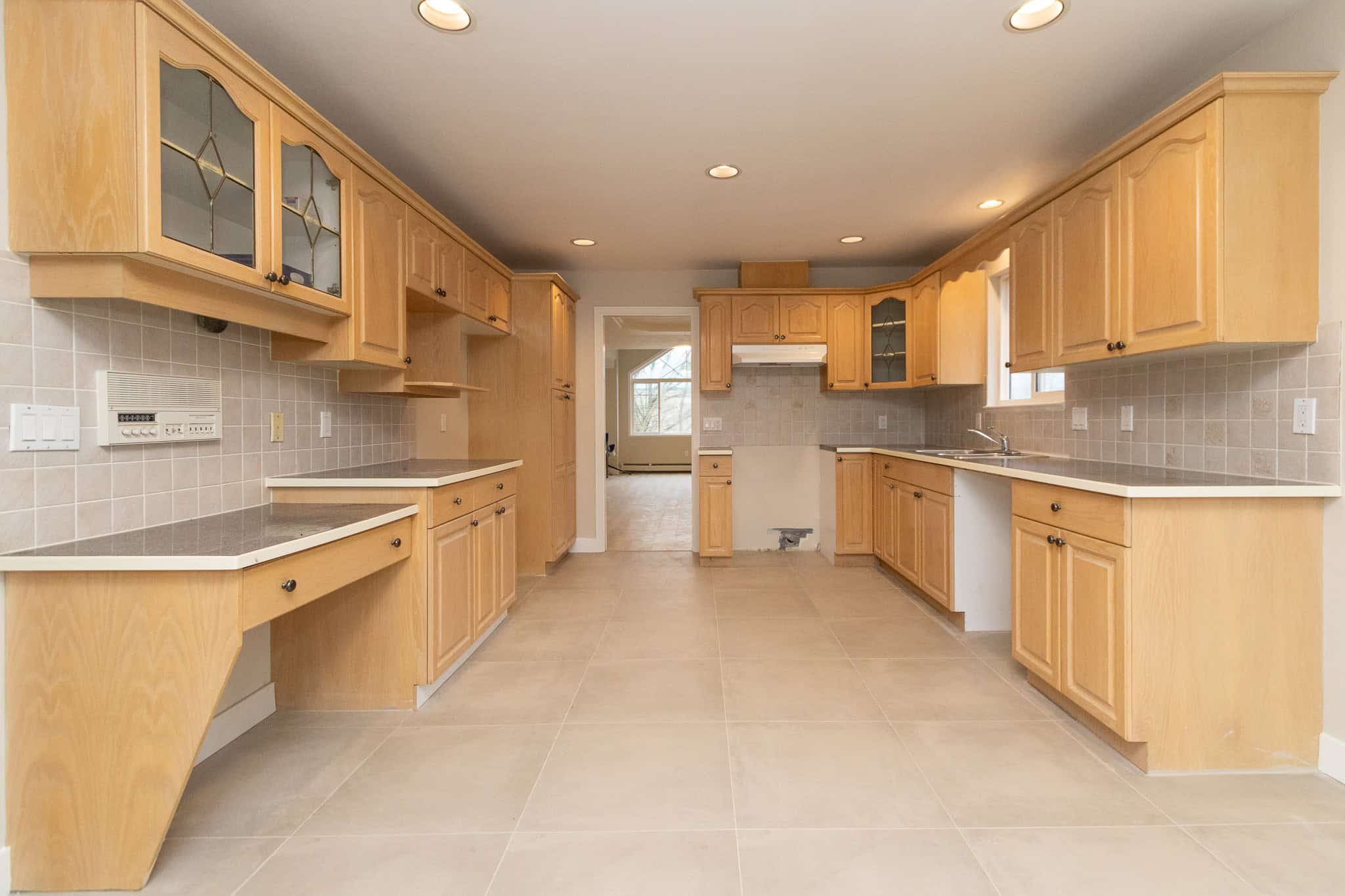 IMG_4333 Bright wooden kitchen cabinets with beige tile backsplash and modern countertops in a spacious home. Perfect for those looking for real estate properties in the Vancouver area.