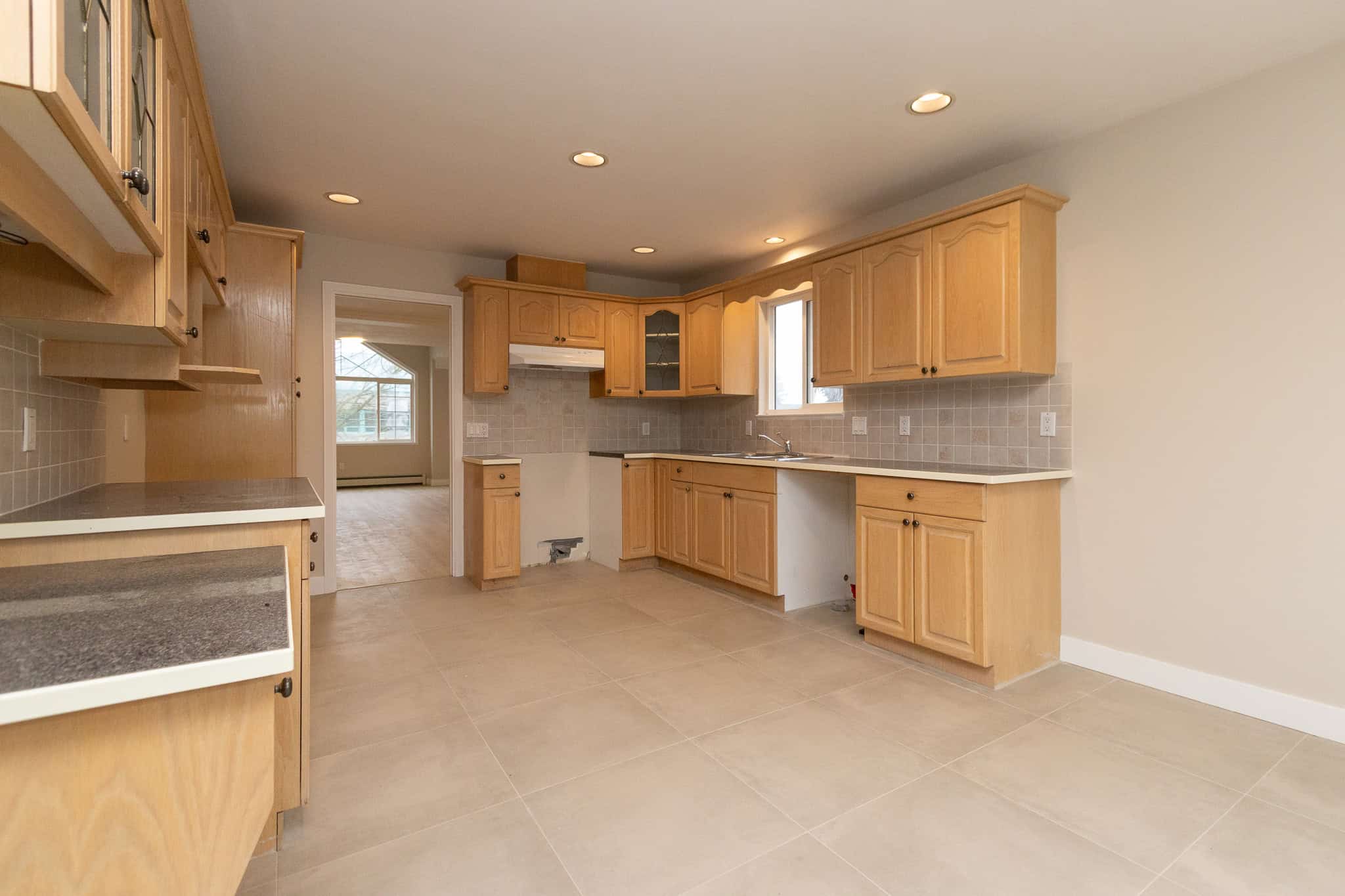IMG_4337 Bright modern kitchen with natural wood cabinetry, beige tiled backsplash, and spacious countertops, ideal for Vancouver Island real estate. Perfect for family living and entertaining in Orca Realty properties.