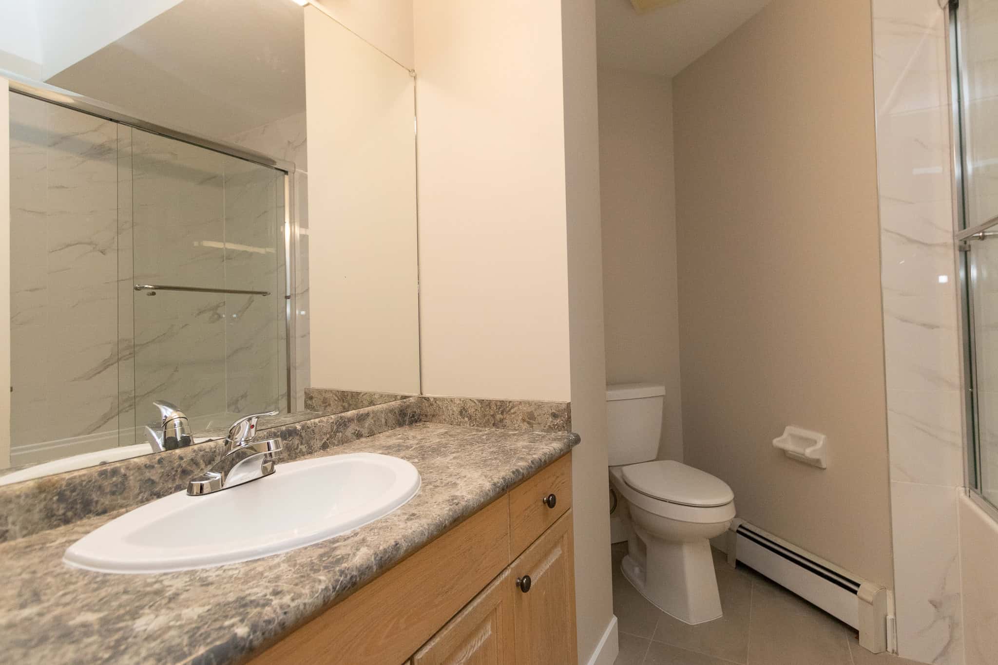 IMG_4354 Bright bathroom with beige walls, granite countertop vanity, white porcelain sink, and modern fixtures in a residential home.