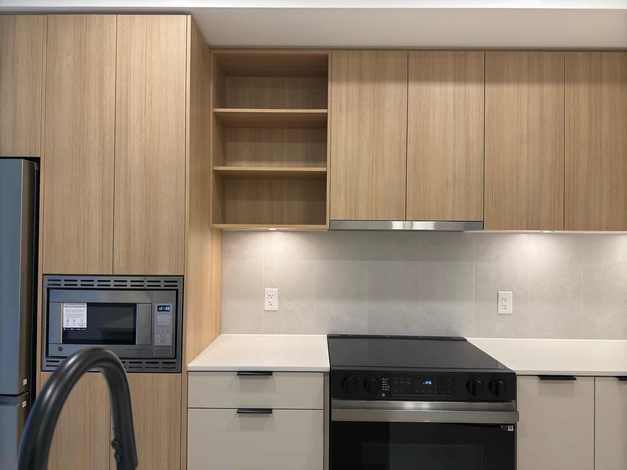 Modern kitchen interior with built-in microwave, stainless steel stove, light wood cabinetry, and minimalist design - ideal for Vancouver real estate listings or property marketing.