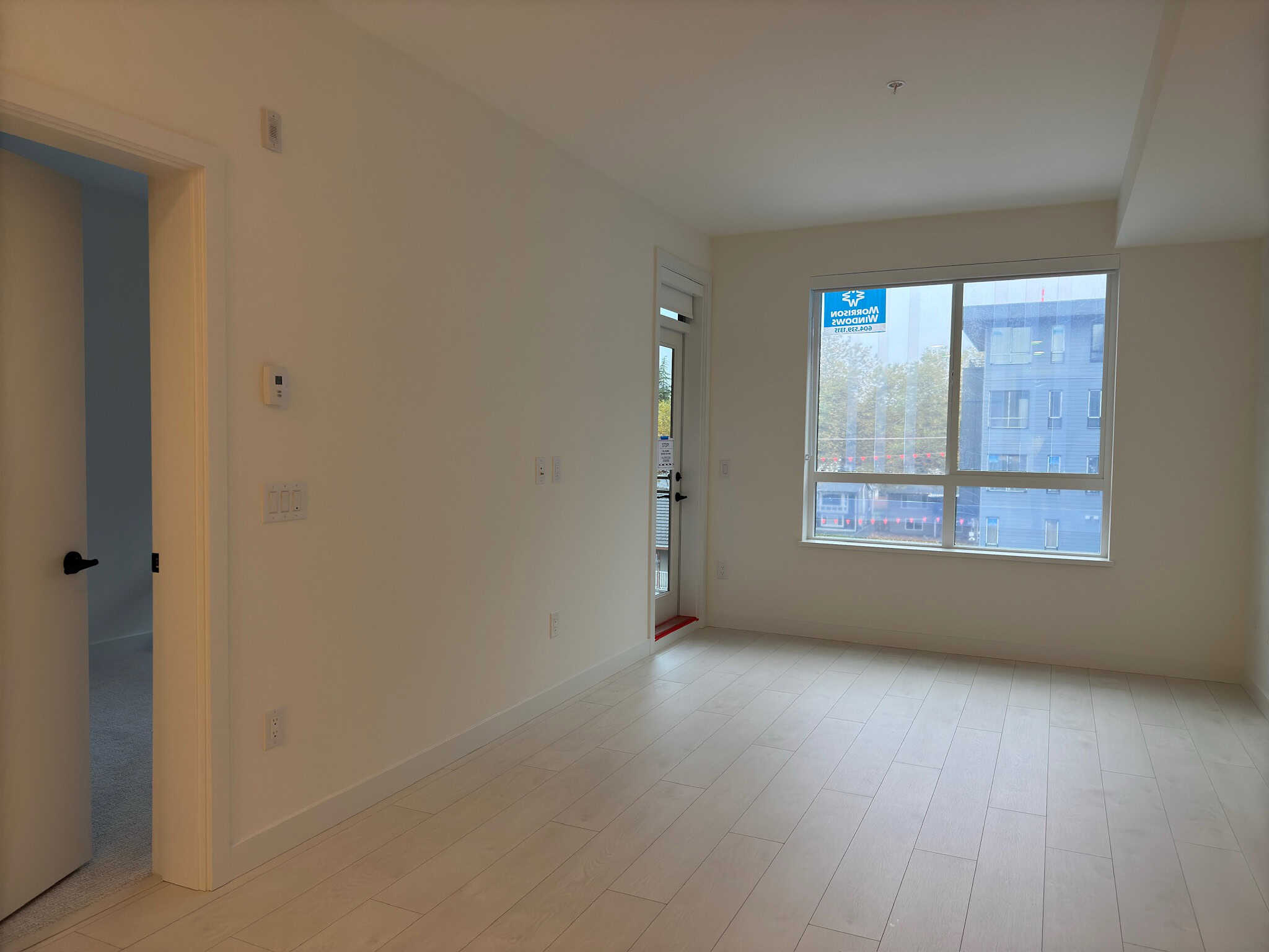 Bright modern living room with large window and neutral decor in a new residential property for sale in Vancouver.