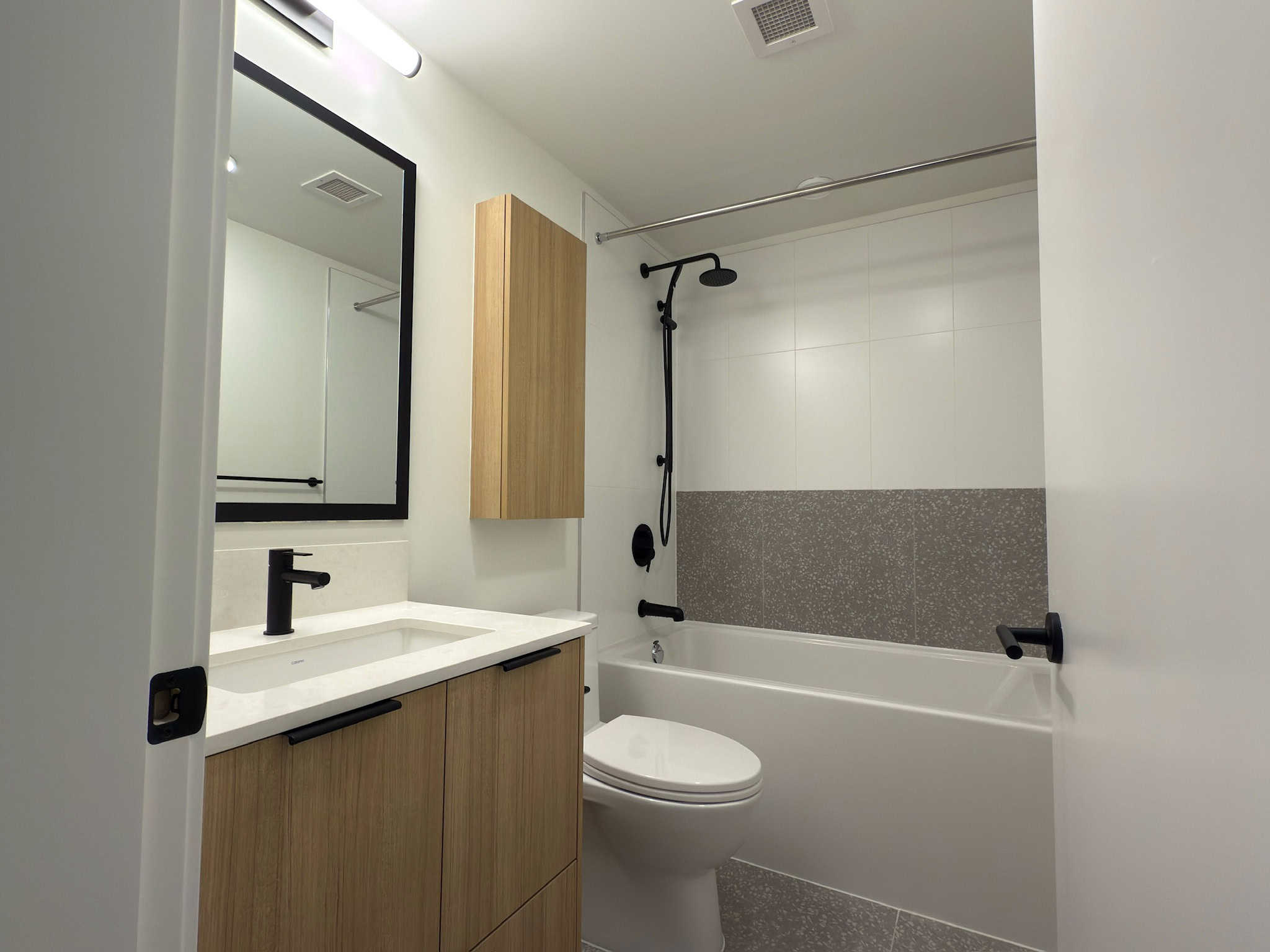Modern bathroom with sleek black fixtures, wooden cabinet, and minimalist design, perfect for contemporary Vancouver homes.
