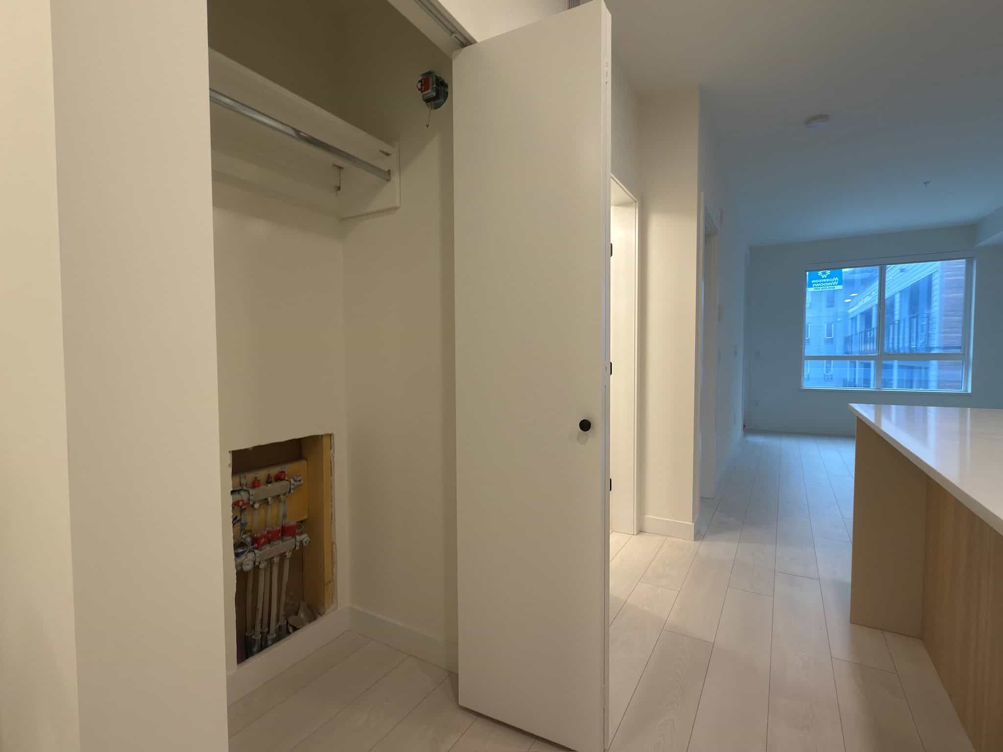 Bright modern condo interior with open living space, large window, light wood flooring, and kitchen island, ideal for urban living in Vancouver, British Columbia.