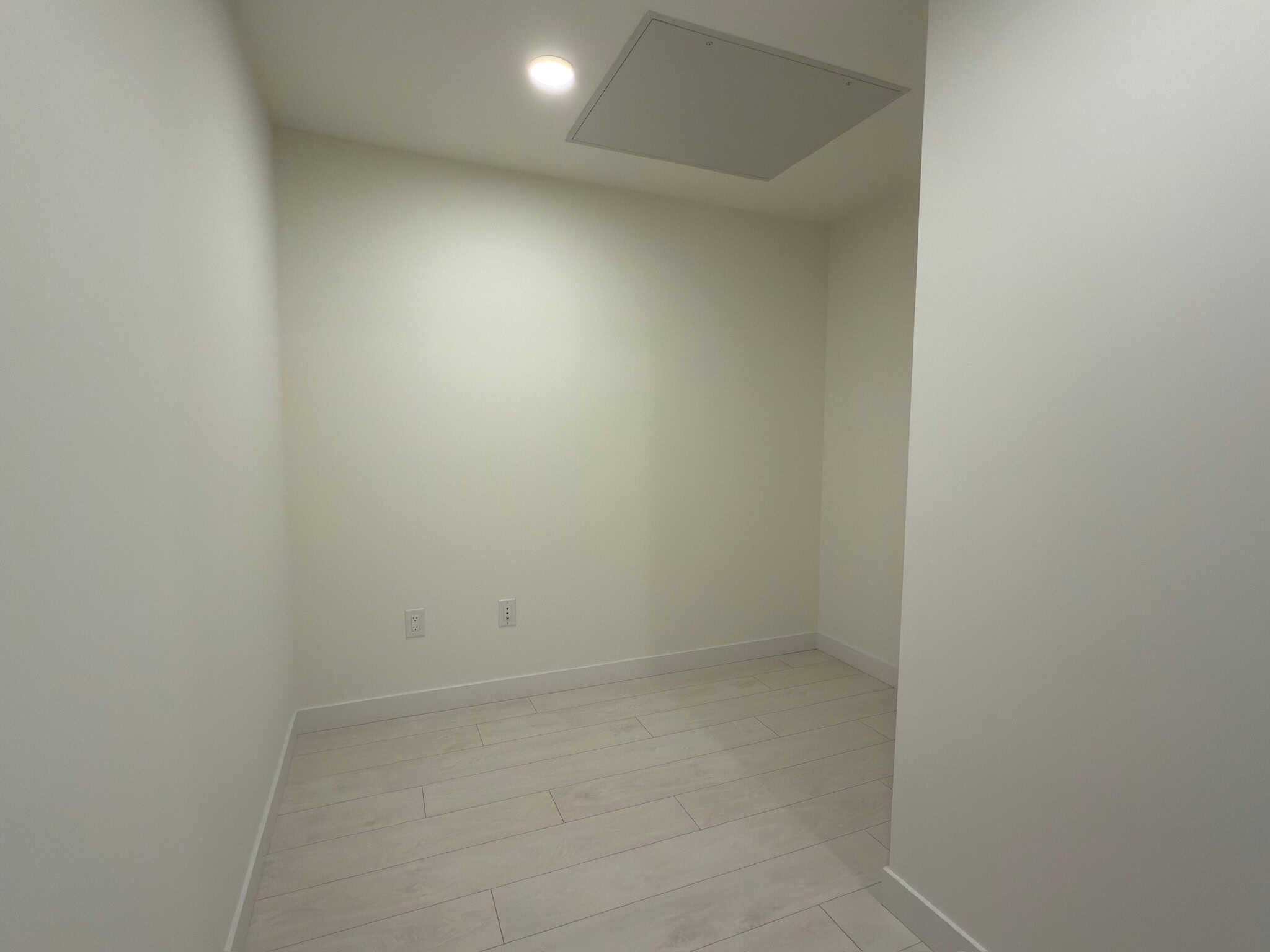 Modern empty room with white walls and light wood flooring, ideal for home office or bedroom, showcasing interior design details for Vancouver real estate.