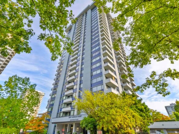 Modern high-rise condo building in Vancouver with glass balconies and lush green trees surrounding it, offering prime real estate opportunities with Orca Realty Inc.