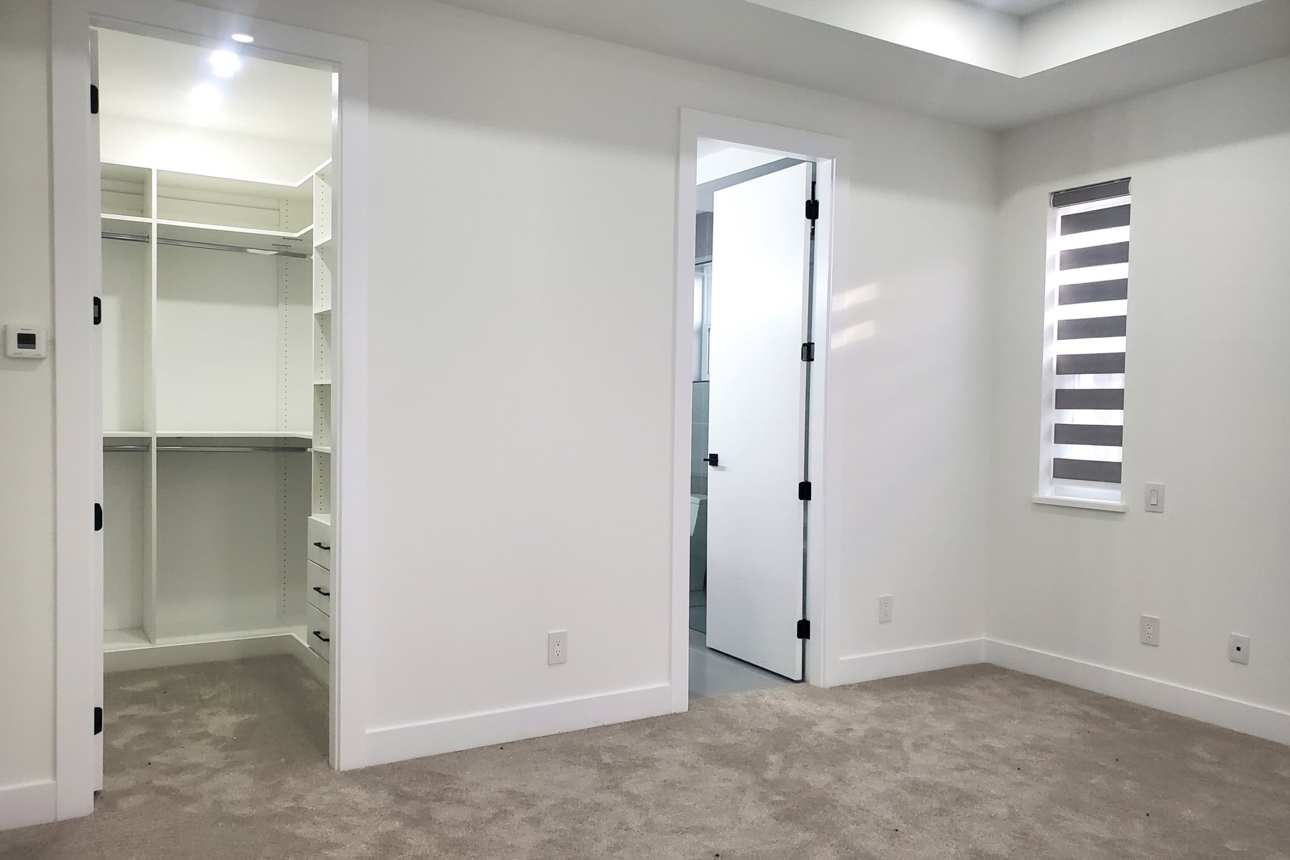 13 Bright modern bedroom with walk-in closet, neutral color palette, and natural light, ideal for real estate listings or property showcases by Orca Realty Inc.
