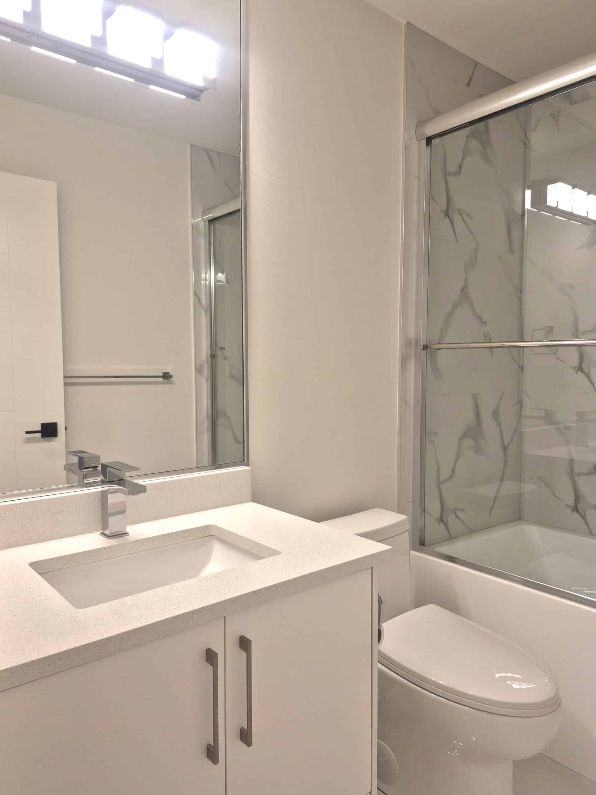Modern bathroom with white vanity, sleek marble shower, and contemporary fixtures, showcasing a clean and stylish interior design perfect for Vancouver real estate.