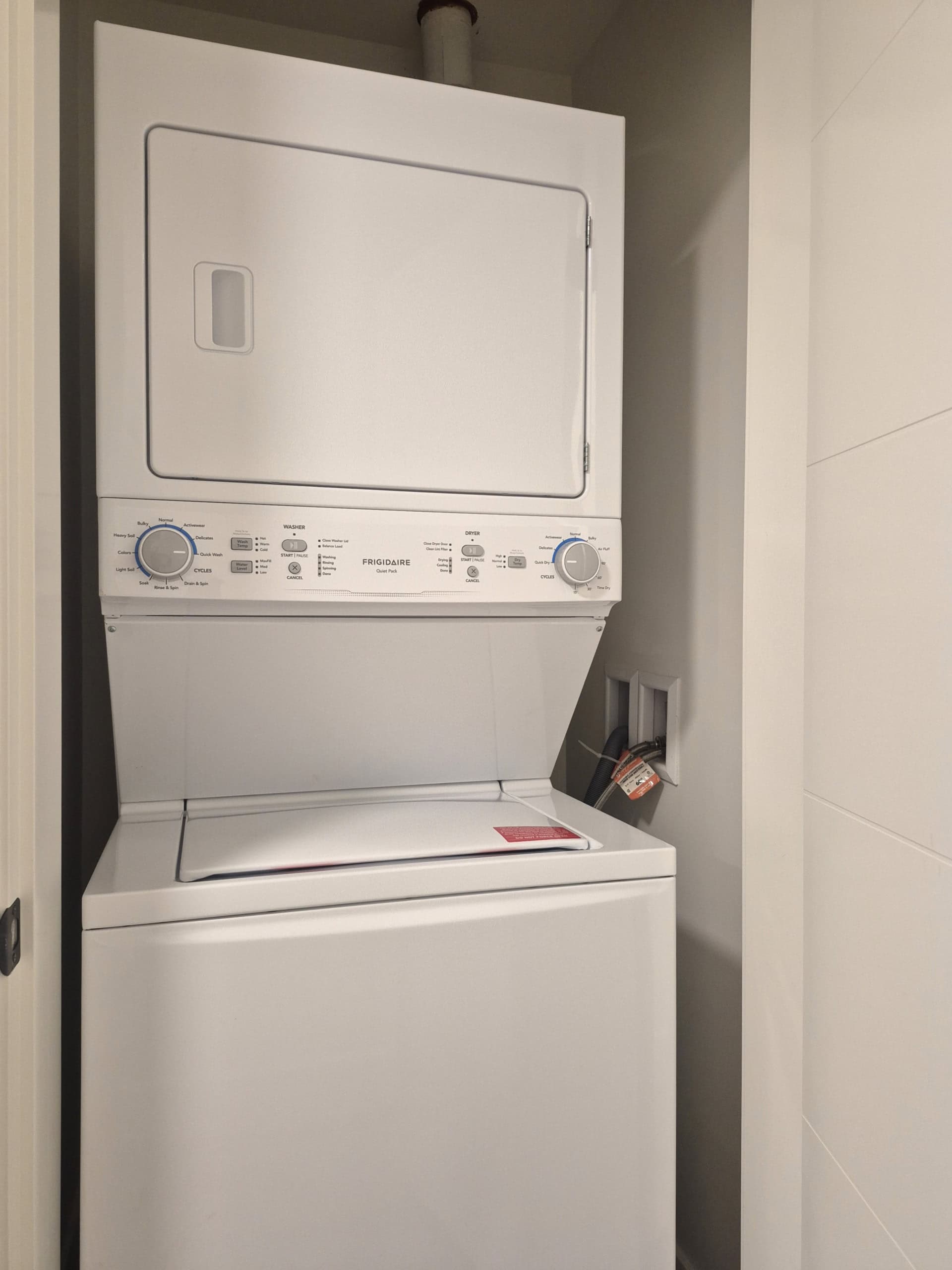 Stacked washer and dryer unit in a modern laundry room, featuring white appliances and space-efficient design, perfect for residential or property rental listings in Vancouver.