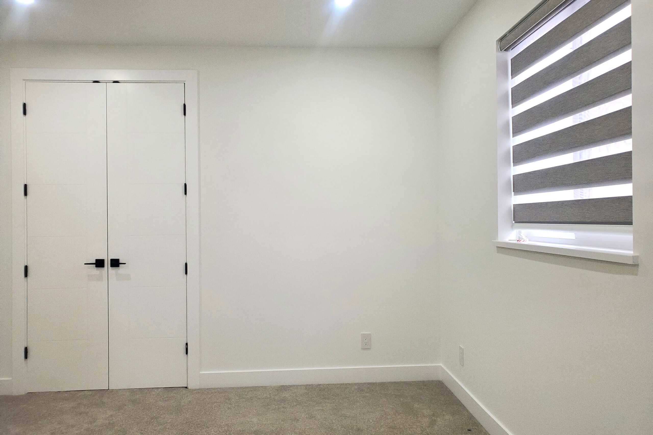 17 Modern empty bedroom with white walls, a double closet, and a window with grey blinds, ideal for home staging or real estate listings in Vancouver.