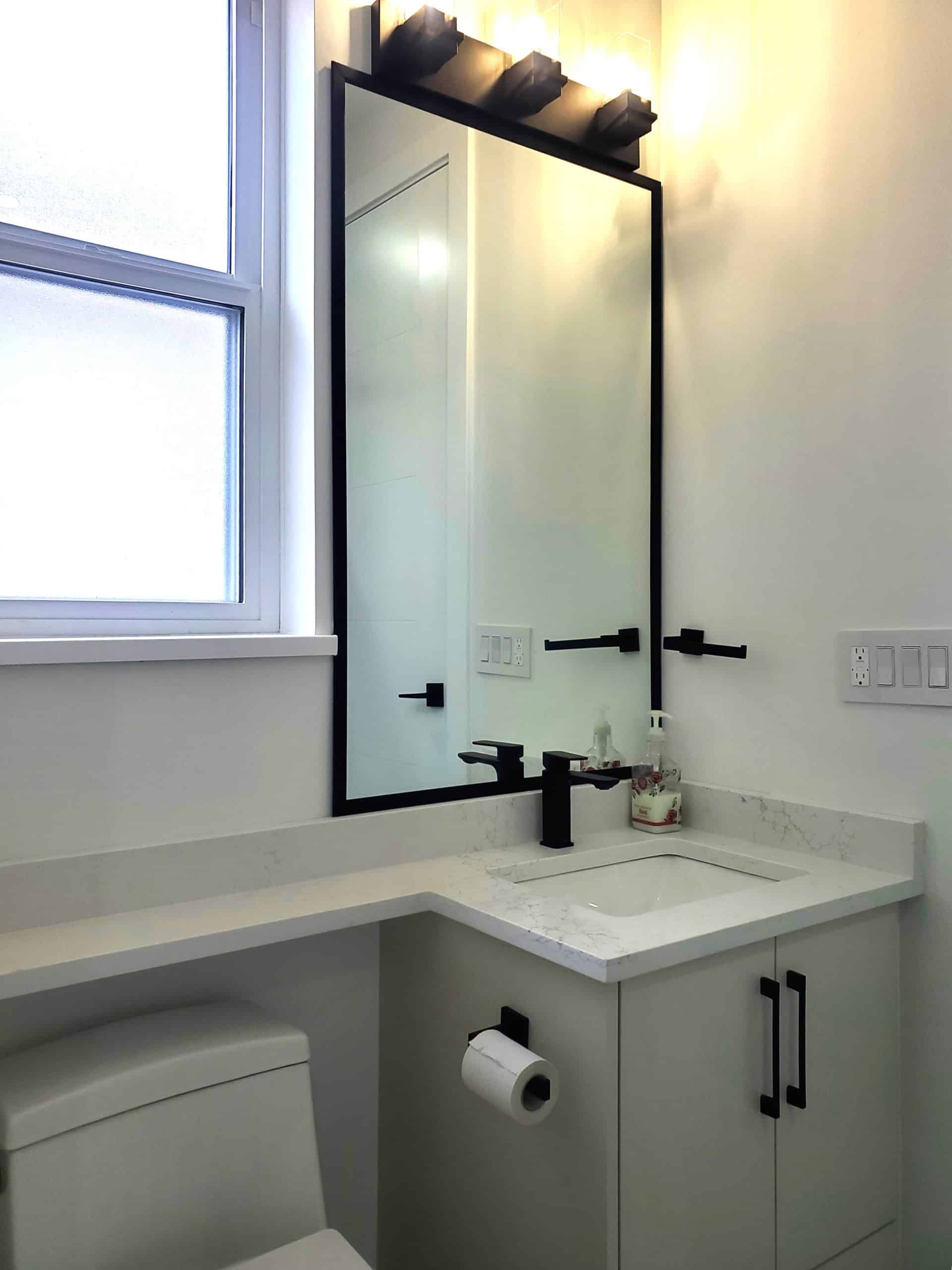 18 Modern bathroom vanity with black fixtures and a large mirror, featuring a white marble countertop and a sleek design, ideal for Vancouver Island homes.