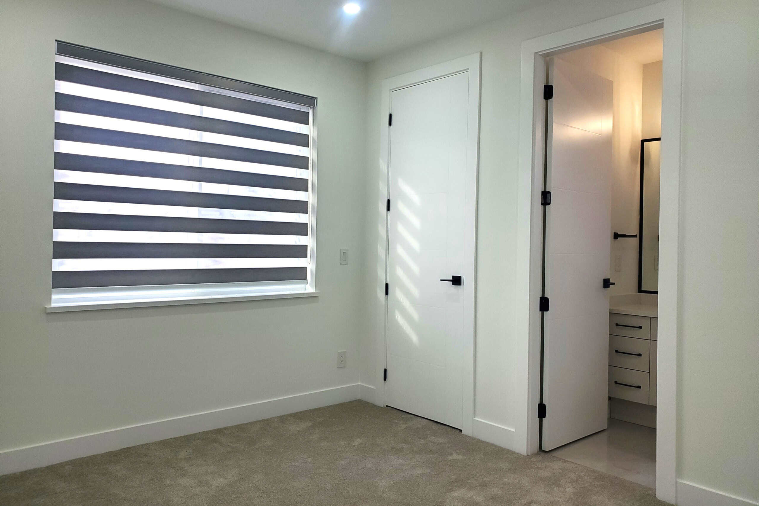 19 Modern bedroom with large window and stylish zebra blinds in a new condo, showcasing contemporary interior design and natural light.