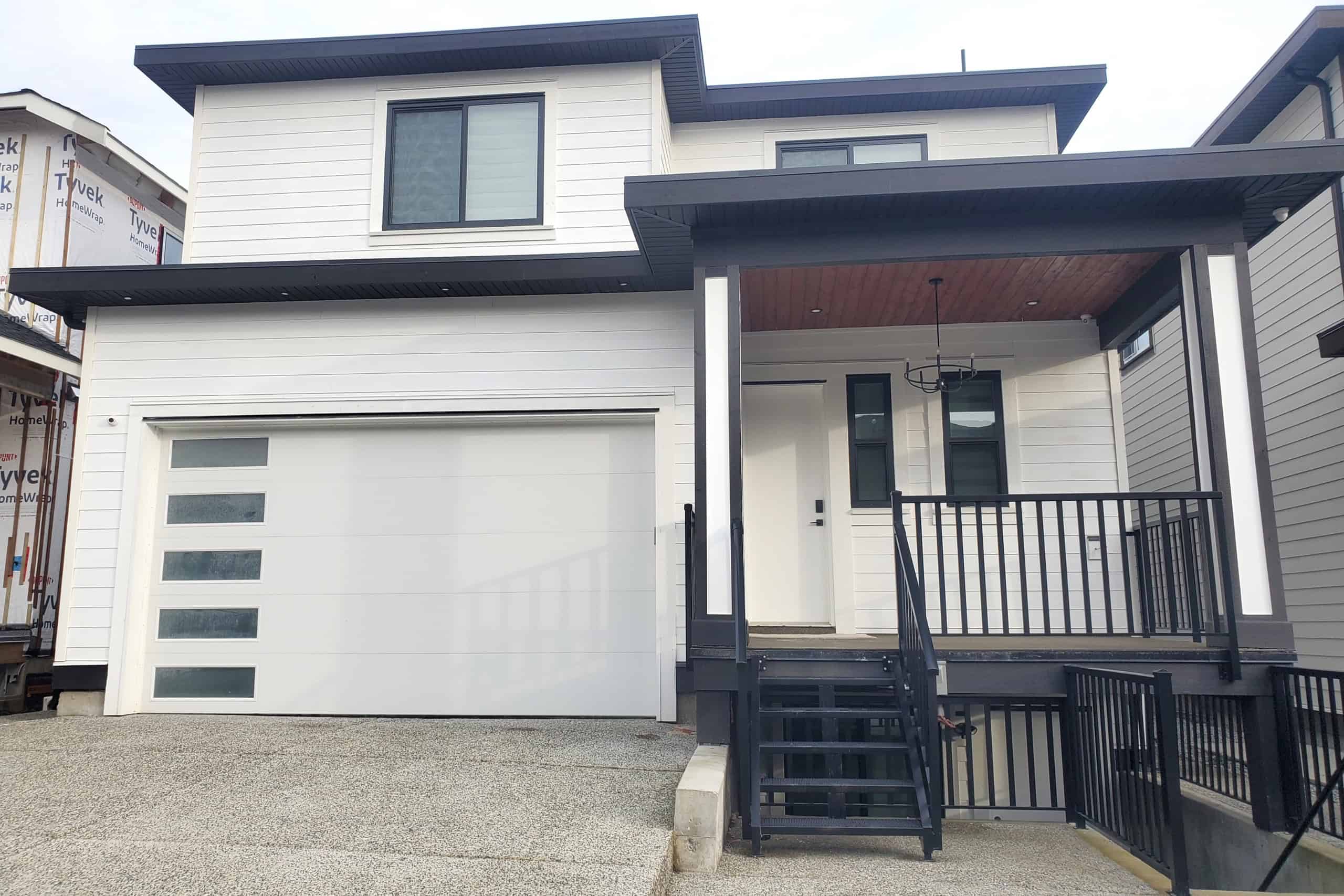 22 Modern new construction home featuring contemporary design, sleek white siding, black accents, and a spacious front porch, perfect for Vancouver real estate investment and family living.