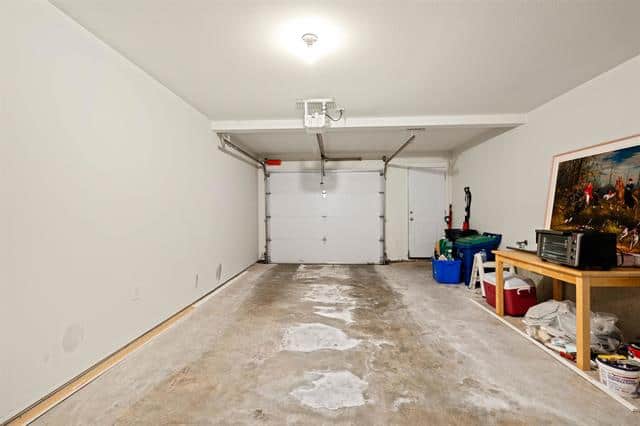 Garage with unfinished concrete flooring and white walls in a residential property.
