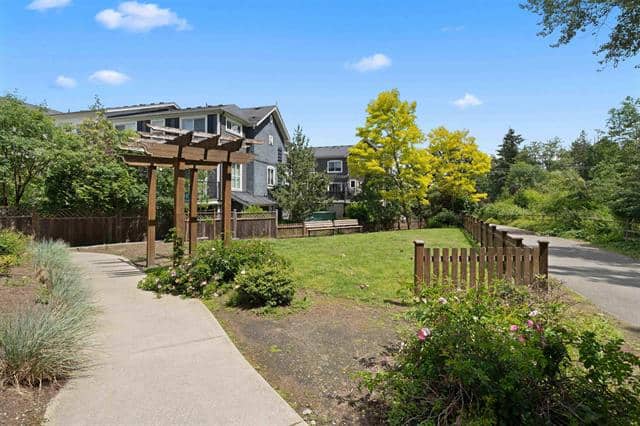 Colorful residential neighbourhood park with walking paths, greenery, and modern multi-story homes in the background, ideal for community living and outdoor activities.