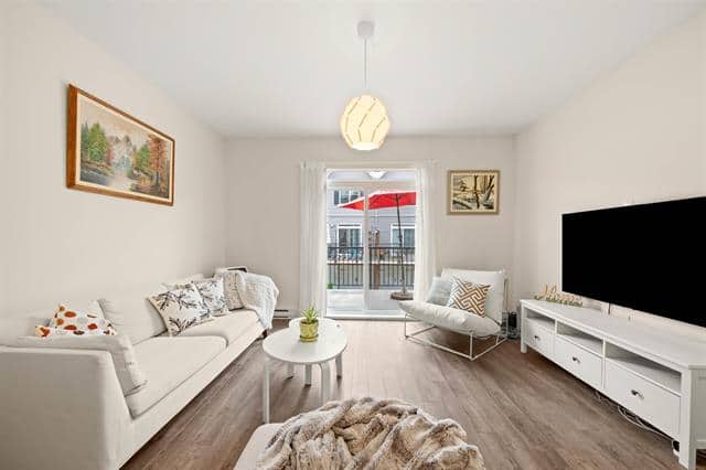 Modern living room with large window, white sofa, and contemporary decor, featuring cozy accents and natural light, ideal for Vancouver real estate listings.