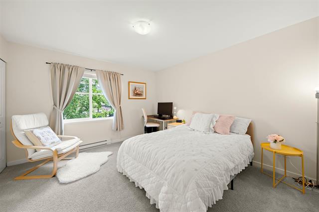 Bright and cozy bedroom featuring a comfortable bed, large window with natural light, and modern decor – perfect for Vancouver Island homebuyers and real estate listings.