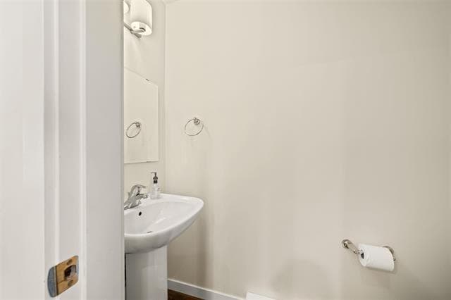 White bathroom with pedestal sink, soap dispenser, and mirror, modern interior design, ideal for Vancouver real estate listing.