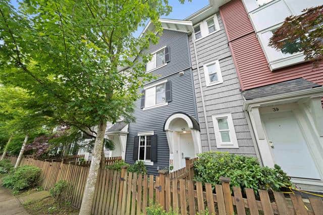 Modern multi-family townhouse with blue and grey siding in a leafy residential neighbourhood in Canada, ideal for real estate investment or family living.