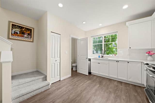 Bright, modern kitchen with white cabinets, large window, and stainless steel appliances, perfect for Ottawa real estate buyers.
