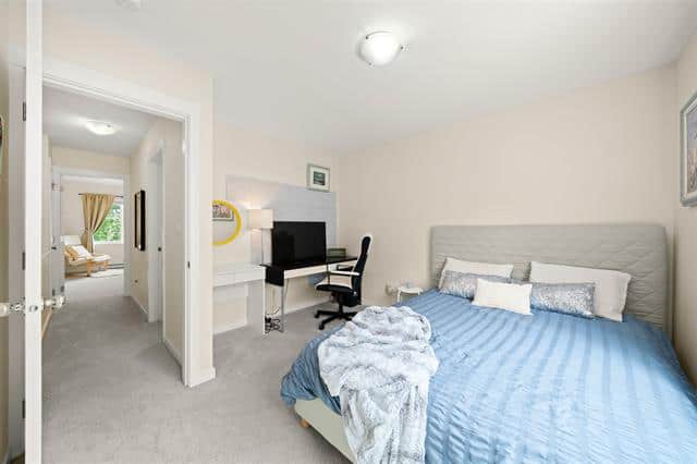 Modern bedroom with blue bedding, workspace, and natural light, showcasing quality rental properties by Orca Realty Inc. in BC.