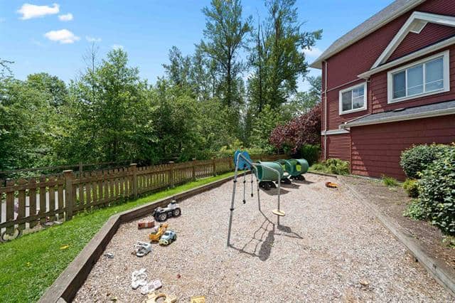 Playground with slide and toys in backyard of red house, family-friendly outdoor space, outdoor play area, residential backyard, safe and fun for children, real estate outdoor features, Orca Realty Inc.