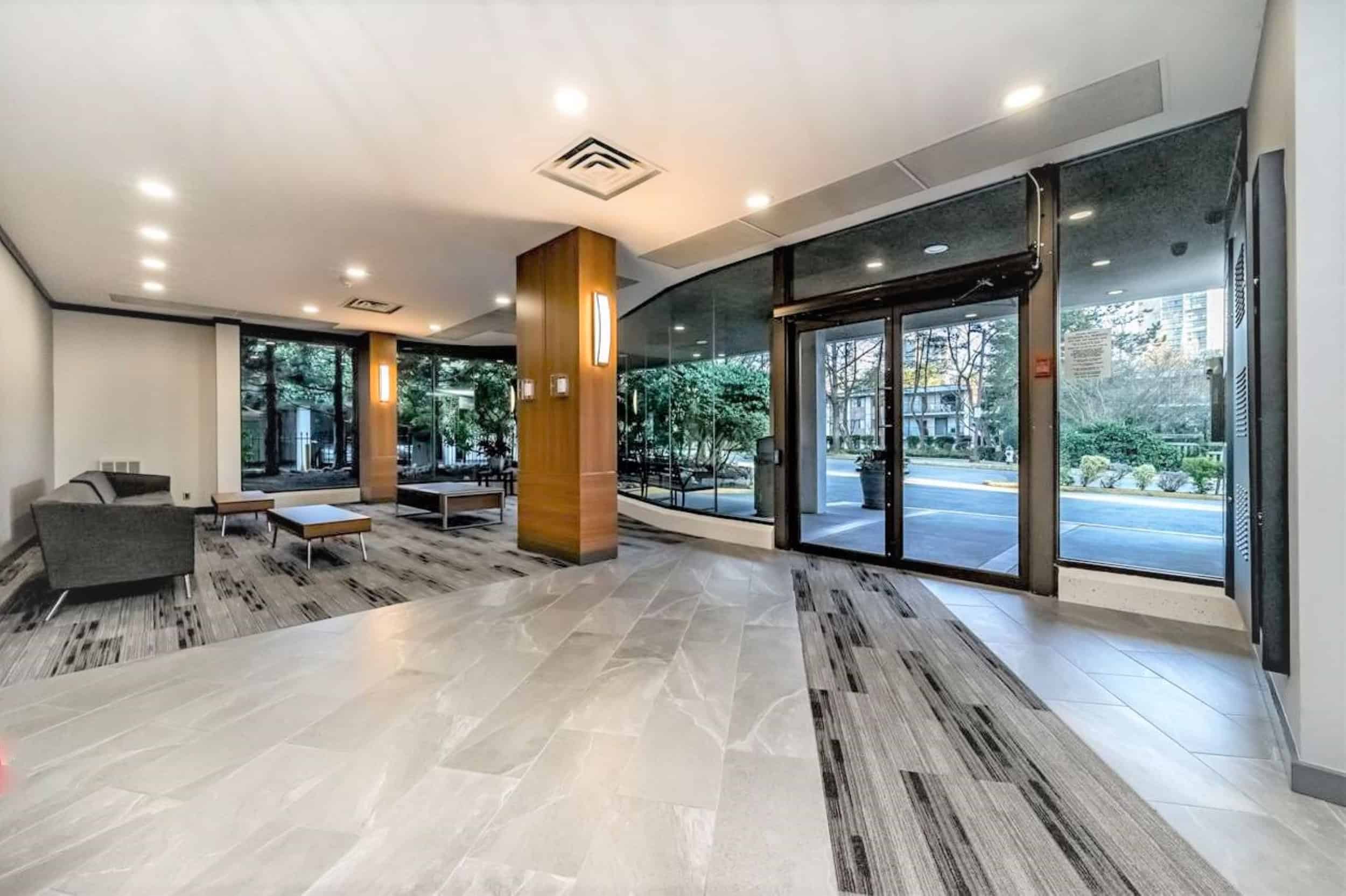 29 Modern condo lobby with large glass windows, sleek flooring, and contemporary furniture, showcasing upscale Vancouver real estate and prime residential property features.