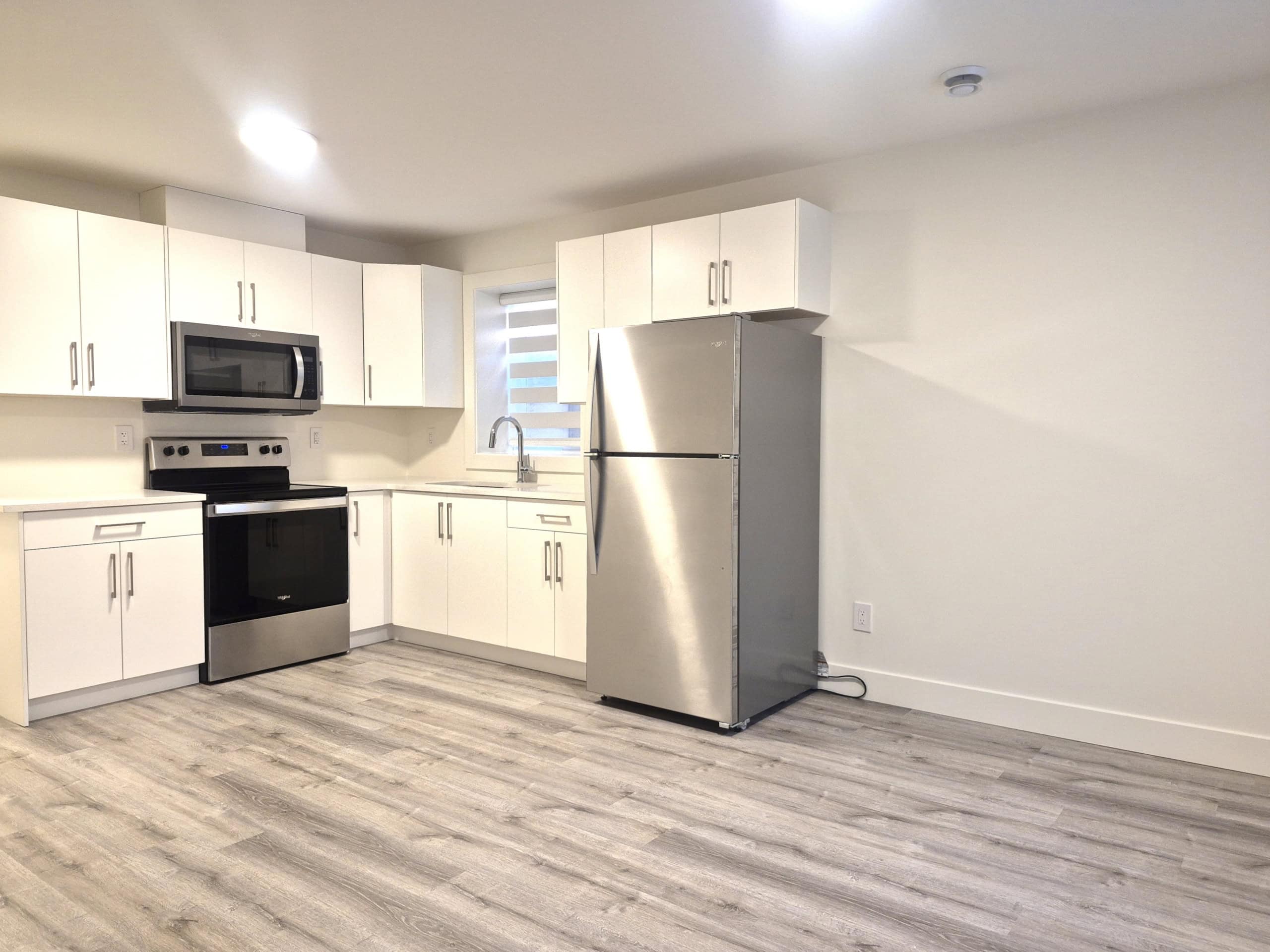 Bright modern kitchen with white cabinets, stainless steel appliances, and light wood flooring, ideal for Vancouver Island real estate and showcasing Orca Realty’s premium properties.