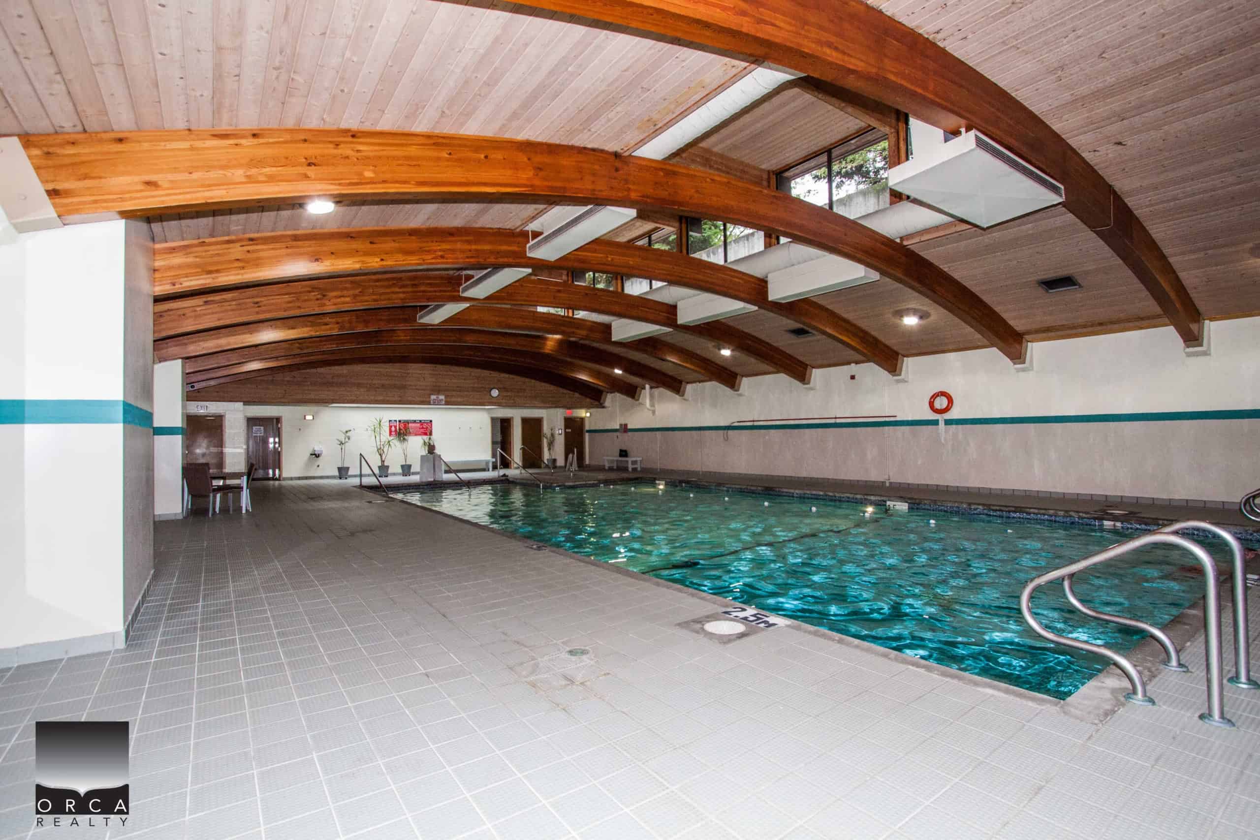 Indoor swimming pool at Orca Realty Inc. showcasing modern amenities, natural wood accents, and a relaxing atmosphere, ideal for Vancouver Island real estate listings and luxurious property features.
