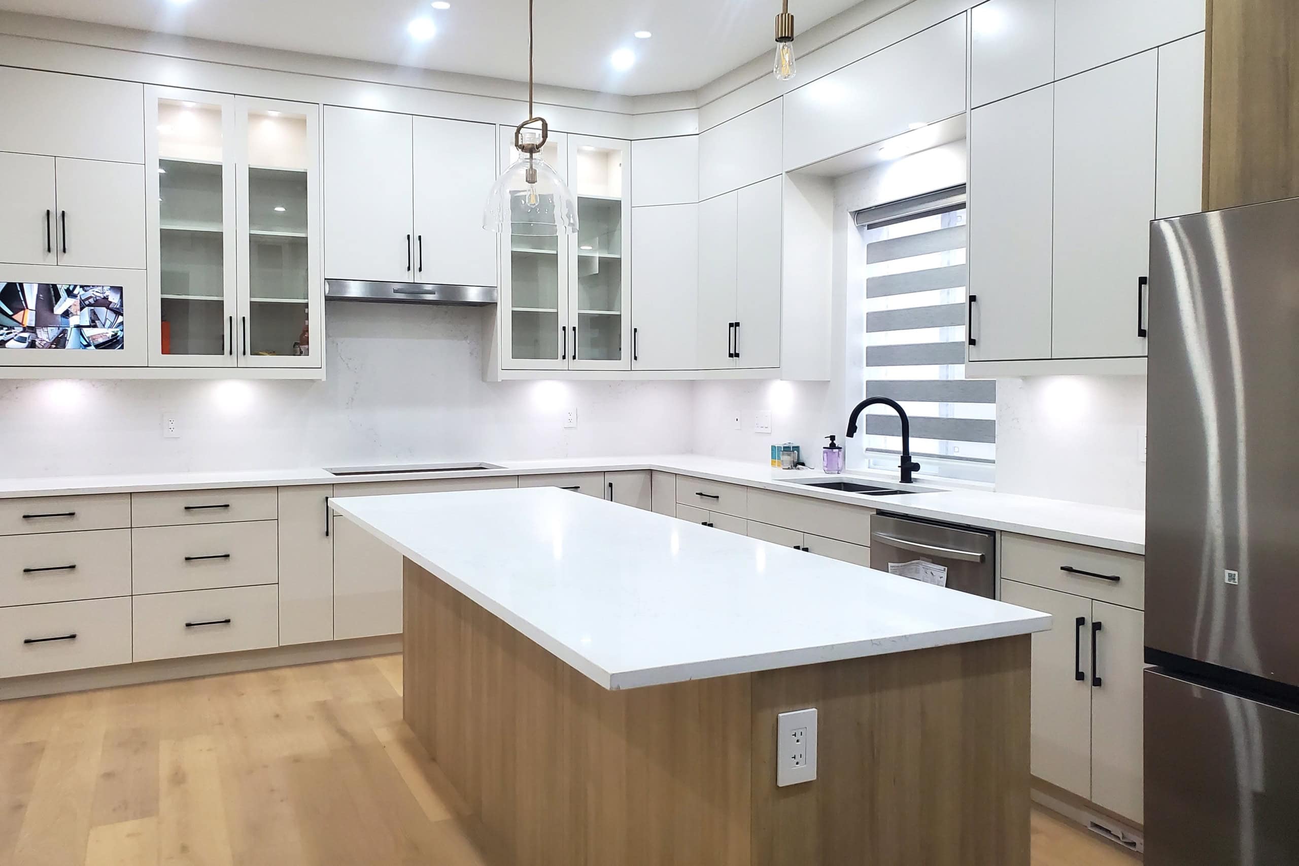 4 Modern white kitchen with sleek cabinetry, large kitchen island, stainless steel appliances, and contemporary lighting for upscale Ottawa real estate listings.
