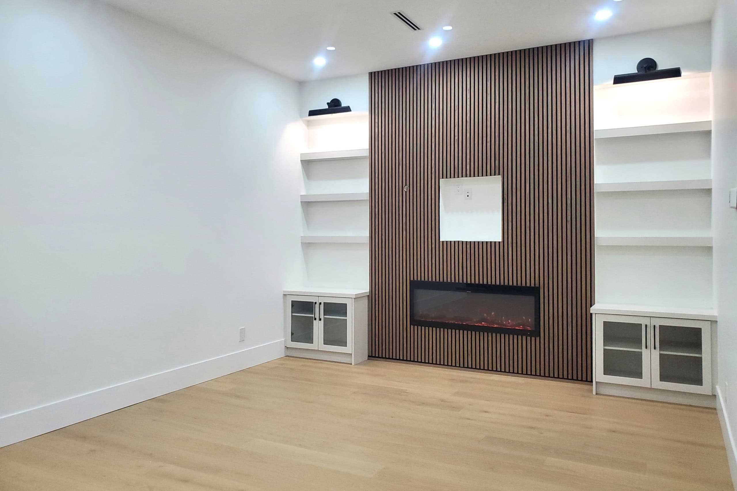 9 Contemporary living room with modern electric fireplace and built-in white shelving, ideal for upscale homes or real estate listings by Orca Realty Inc.
