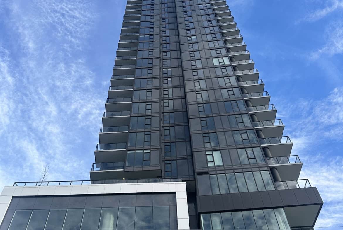 Contemporary high-rise condo building with glass exterior, featuring spacious balconies, located in a vibrant urban area in Vancouver. Perfect for modern downtown living and real estate investment.