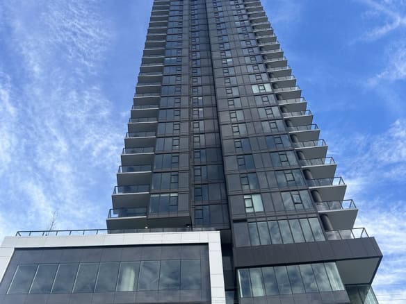 Contemporary high-rise condo building with glass exterior, featuring spacious balconies, located in a vibrant urban area in Vancouver. Perfect for modern downtown living and real estate investment.