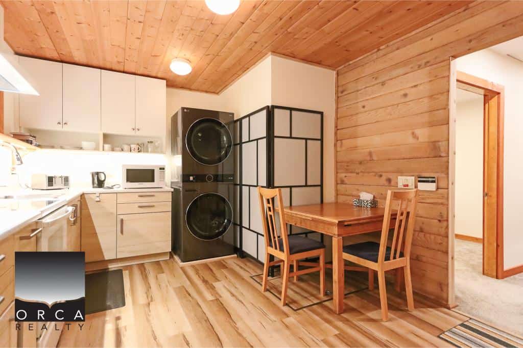 Cozy kitchen and dining area in a modern cabin-style home with wooden accents, ample storage, and contemporary appliances in a property listed by Orca Realty Inc.