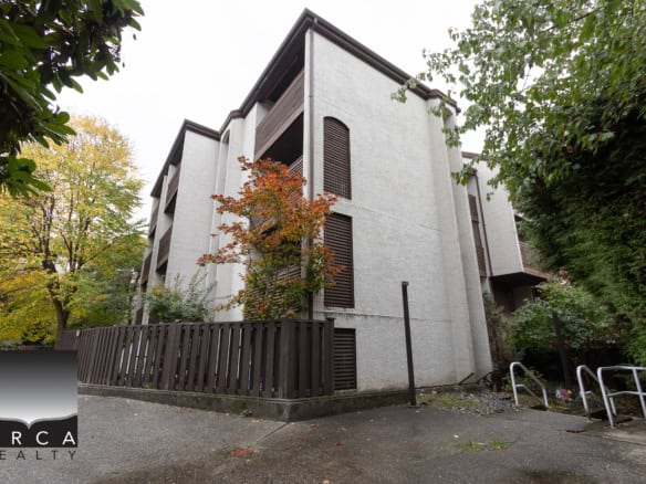 Modern white multi-family residential building with wooden shutters surrounded by fall foliage in Victoria, BC.