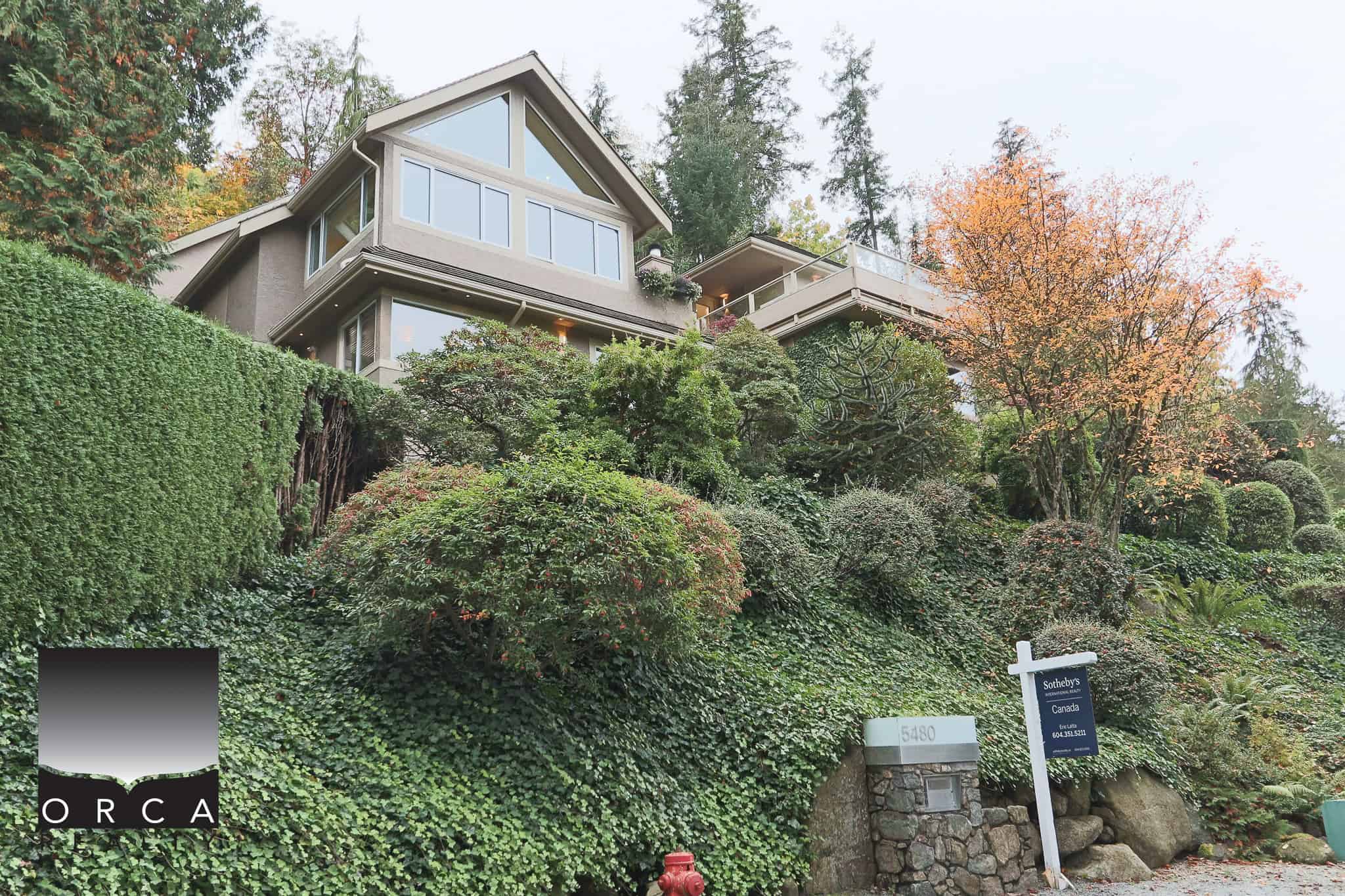 Luxurious modern home perched on a lush, landscaped hillside in Vancouver, British Columbia, showcasing stunning architecture, expansive windows, and exquisite views, ideal for luxury real estate buyers.
