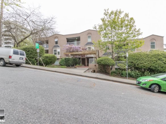 Modern apartment building with landscaped surroundings in Vancouver, BC, featuring parking and residential units.