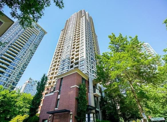 Modern high-rise condominium building in downtown Vancouver, BC, surrounded by green trees.