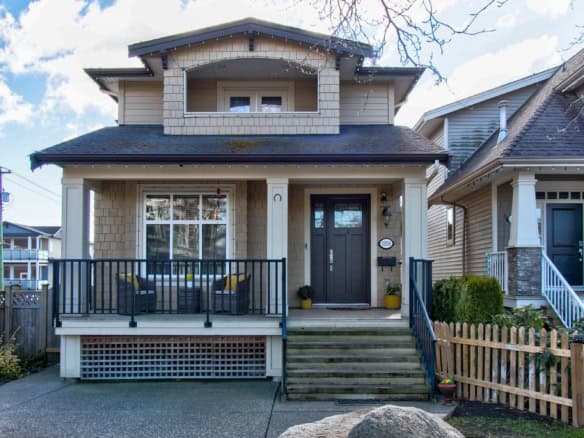 Charming Vancouver-style home featuring a spacious front porch, modern black door, and well-maintained landscaping, perfect for families and showcasing prime real estate in BC.